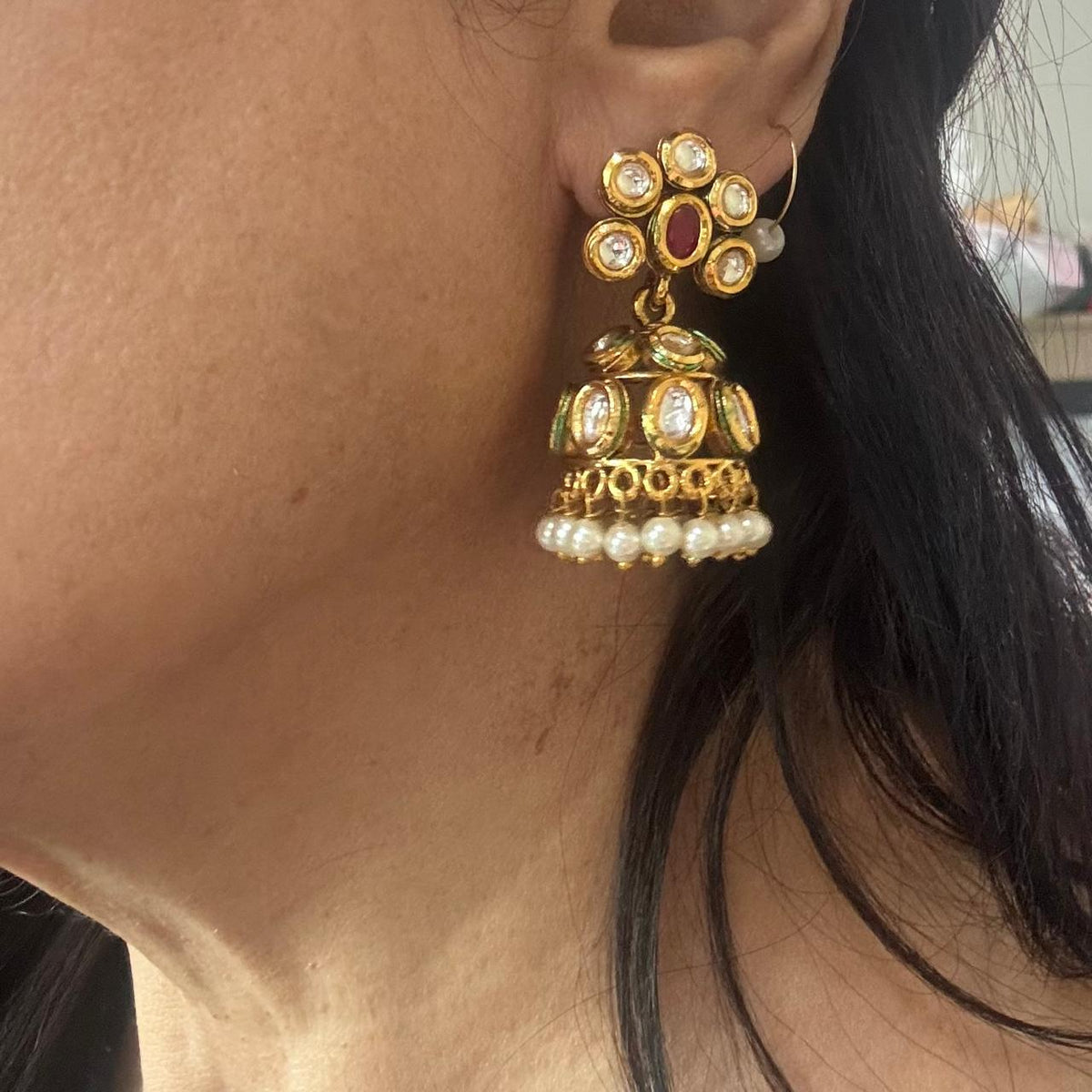 close up of women wearing Ruby and white stone Kundan jhumka earrings with pearl drop border