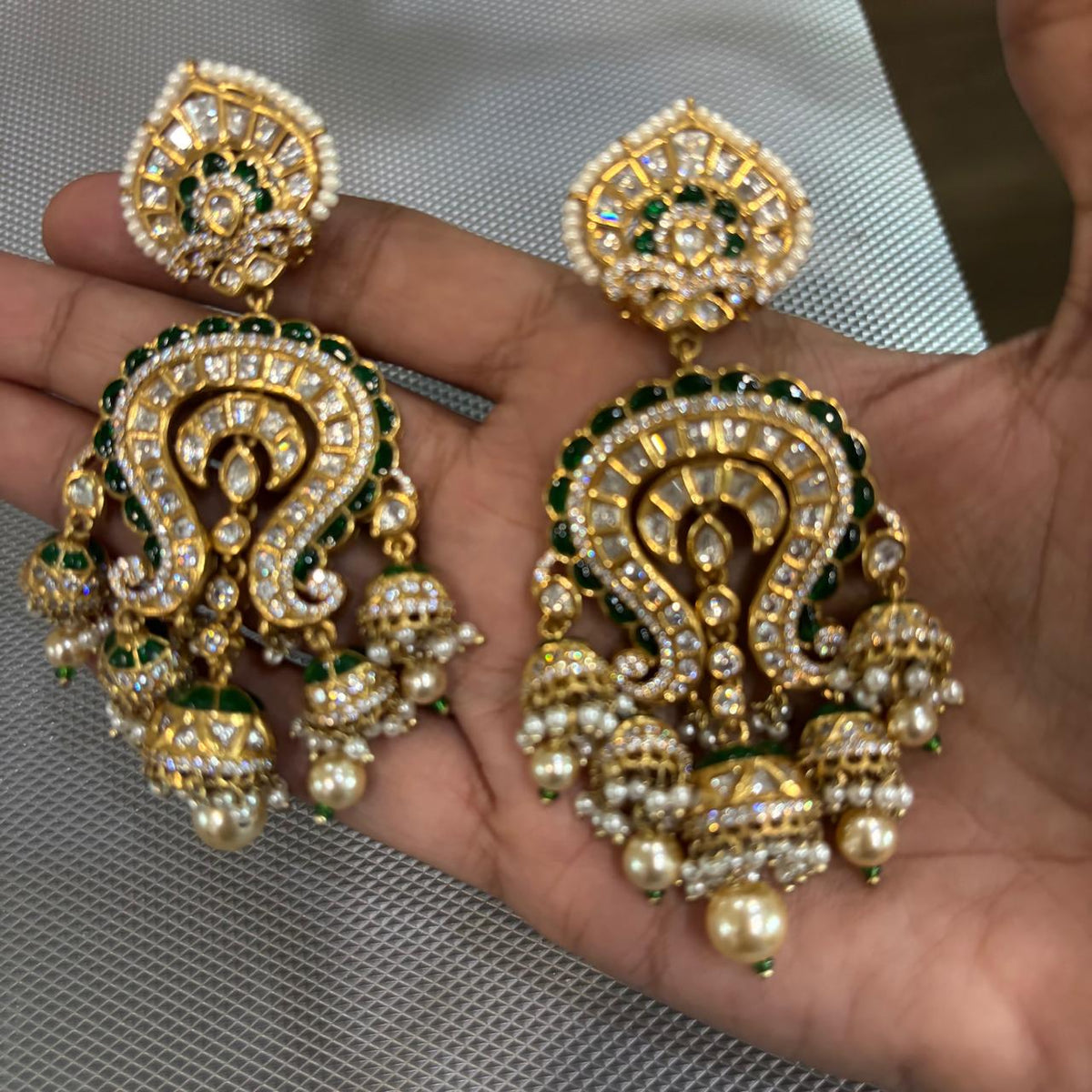 Close up of Statement wedding earrings with green enamel and kundan and dangling pearl jhumkas earrings