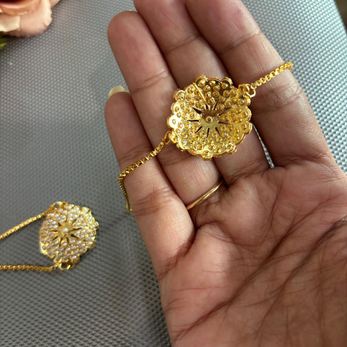 Back side of Pearl jadau bracelet rakhi in gold tone on hand