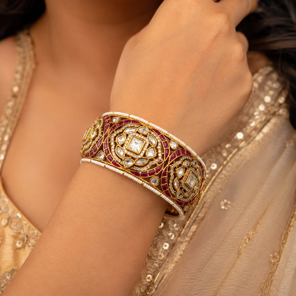 Women wearing Openable Gold tone moissanite Polki kada with ruby detailing , pearls and uncut diamonds