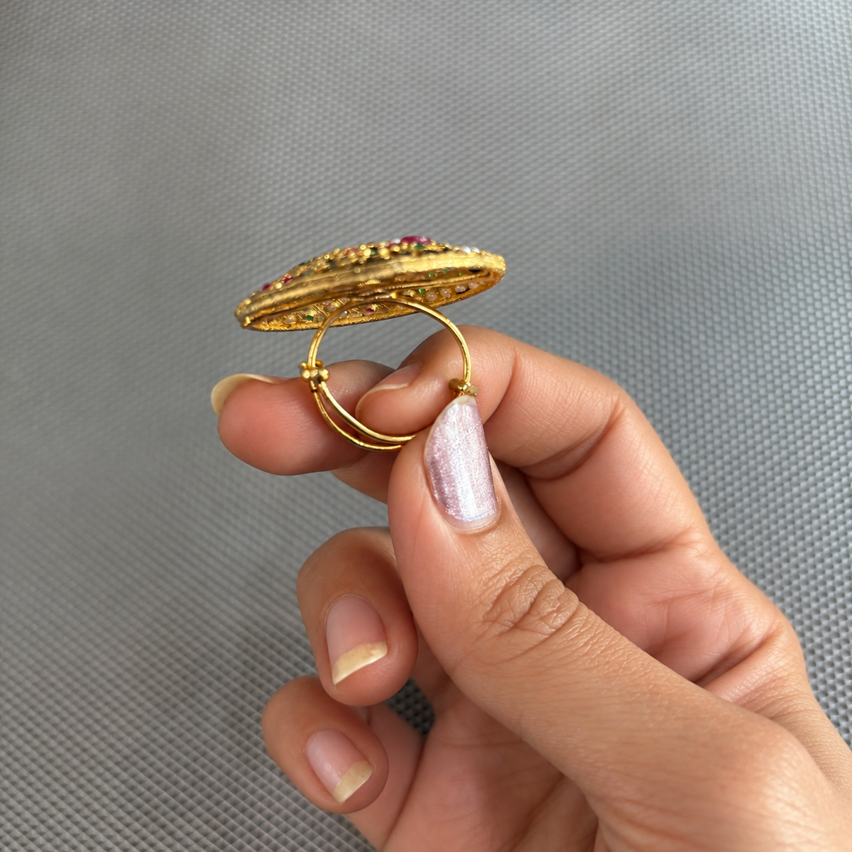 Side view of the Maahi multicolour Jadau floral statement ring held in a hand, showing its gold adjustable band