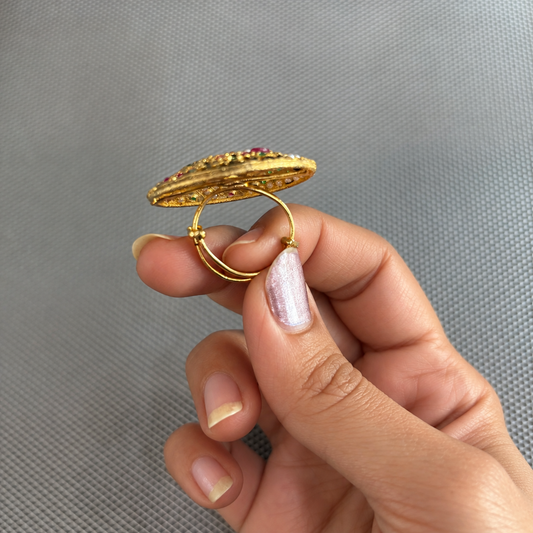 Side view of the Maahi multicolour Jadau floral statement ring held in a hand, showing its gold adjustable band