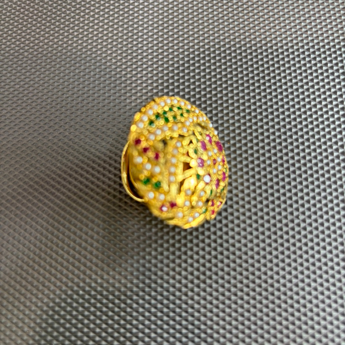 Angled view of the Maahi multicolour Jadau floral statement ring with pink and green stones and white accents on a grey textured surface