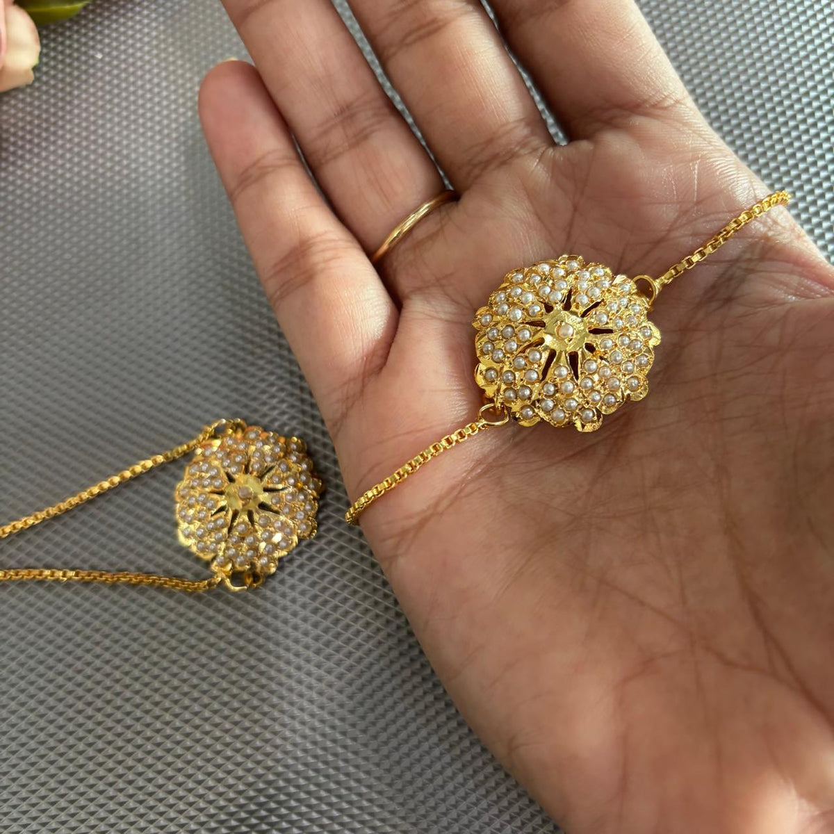 Pearl jadau bracelet rakhi in gold tone on hand