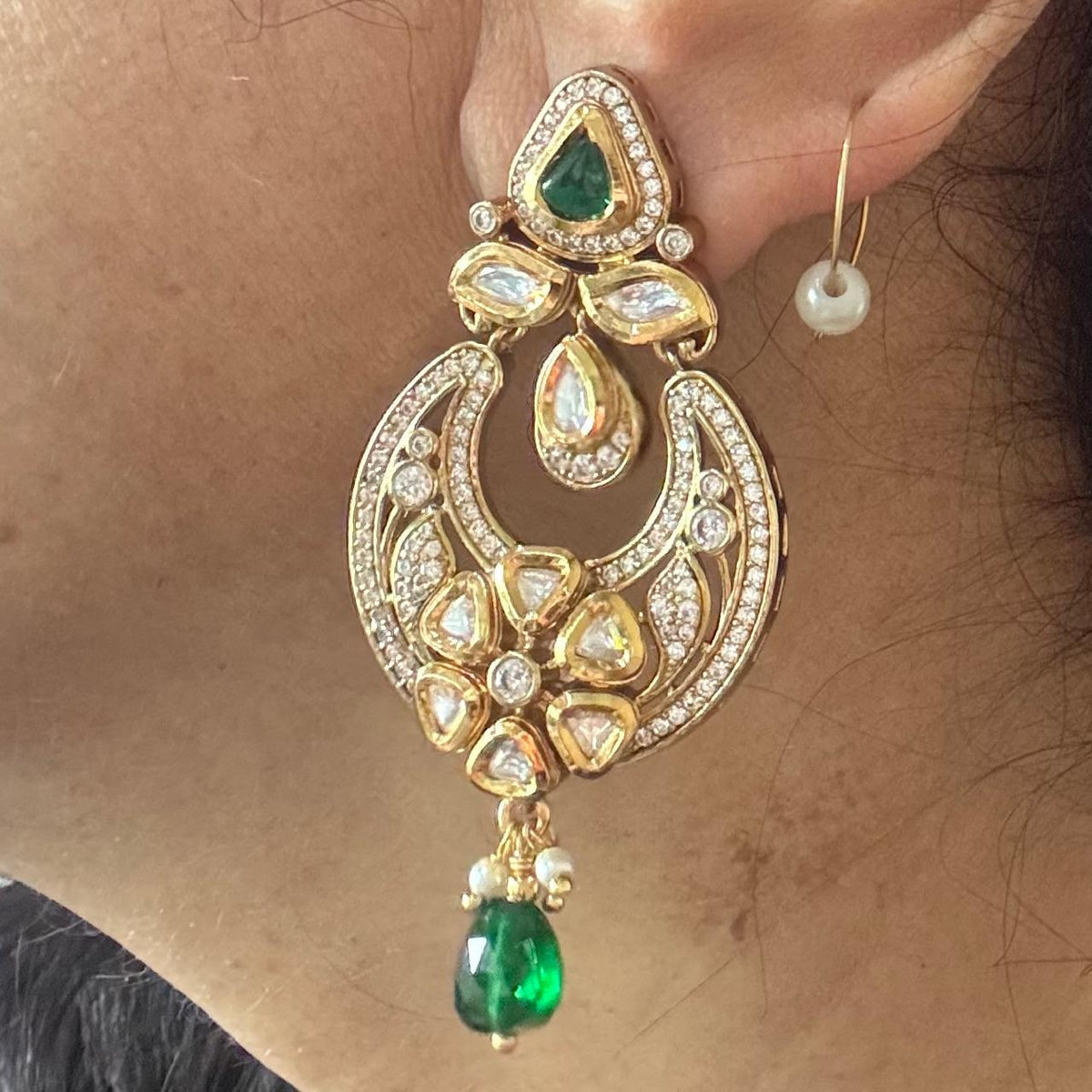 Close up of Women wearing Polki moissanite chandbali earrings with AD stones and emerald drops