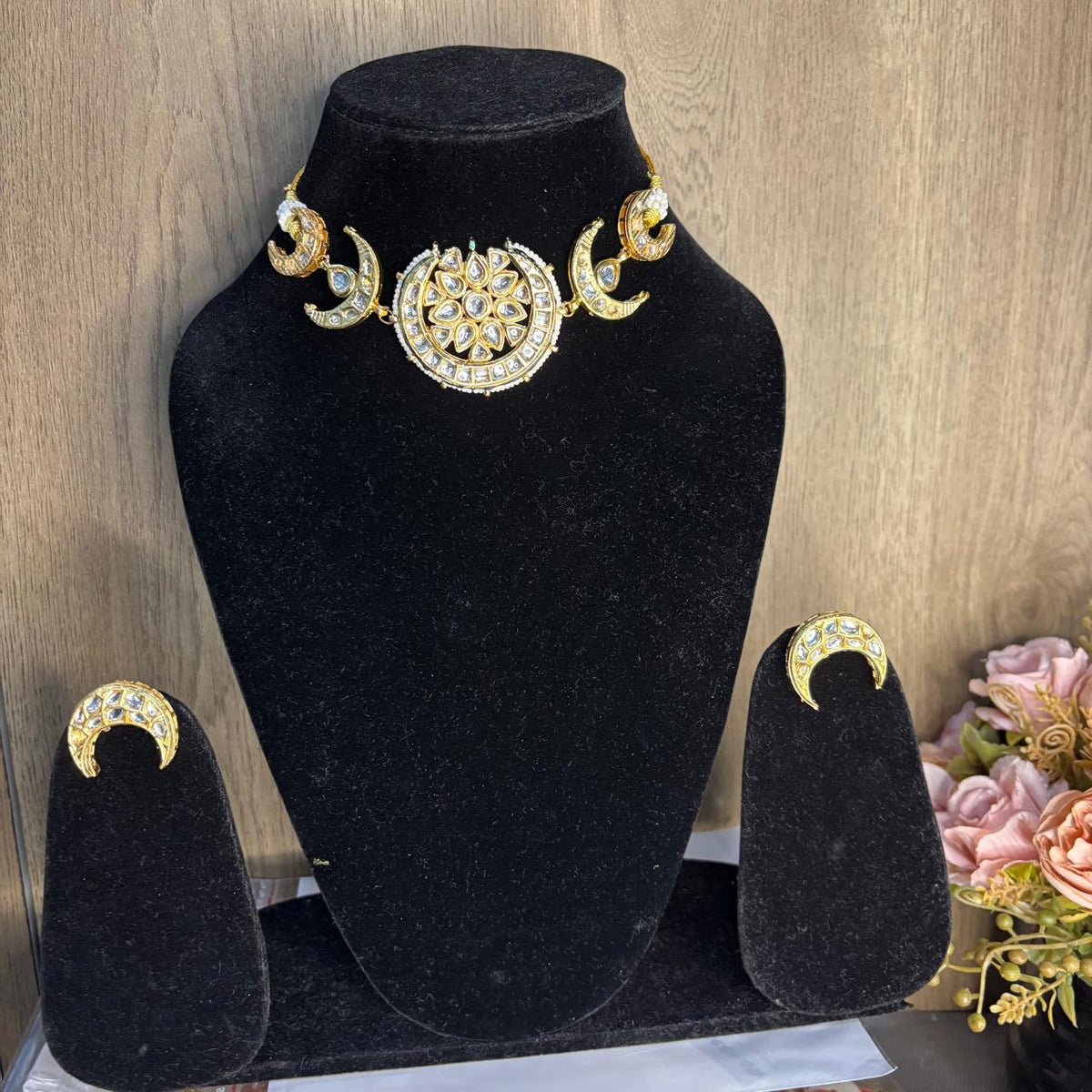 Front view of  crescent moon choker  necklace  set with white Kundan stones and pearl border in gold plating 