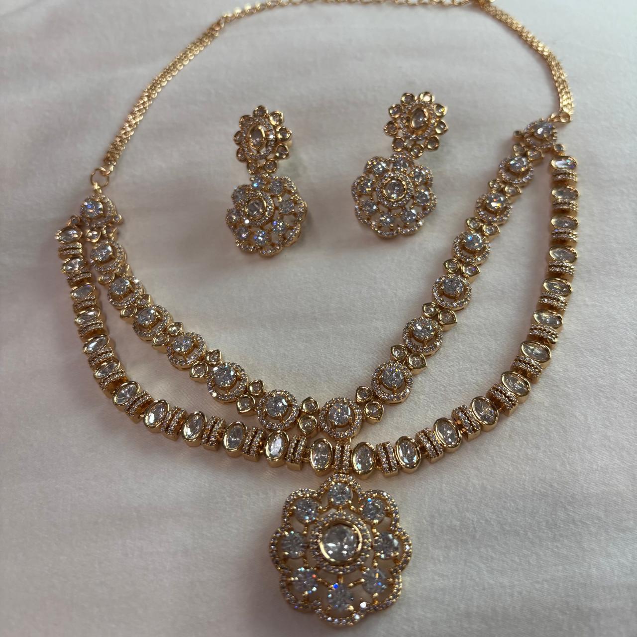 Ahana double layer solitaire American Diamond necklace set with floral pendant and matching earrings in gold finish for bridal and party wear.