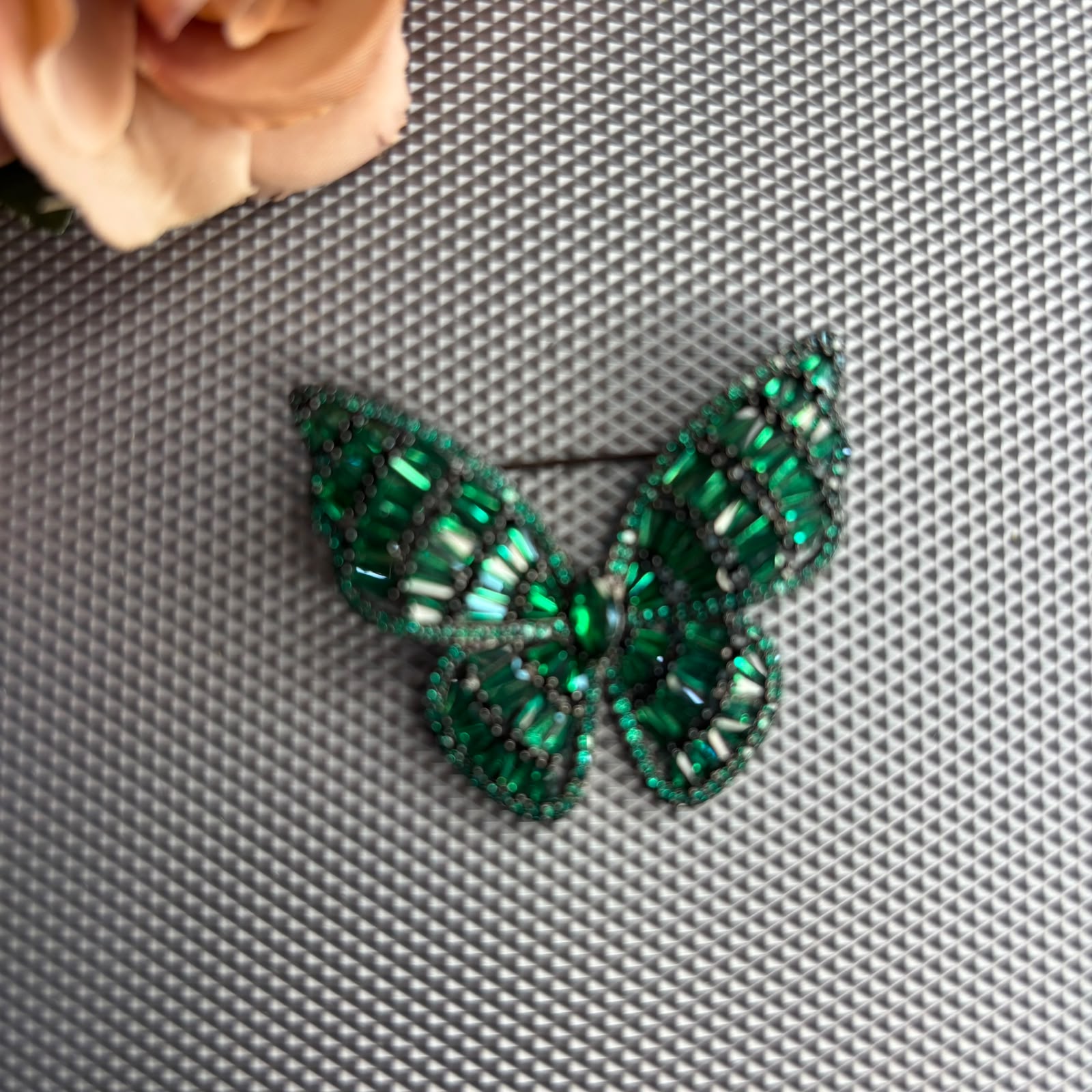 Emerald green crystal butterfly brooch with black rhodium finish and premium baguette stones.