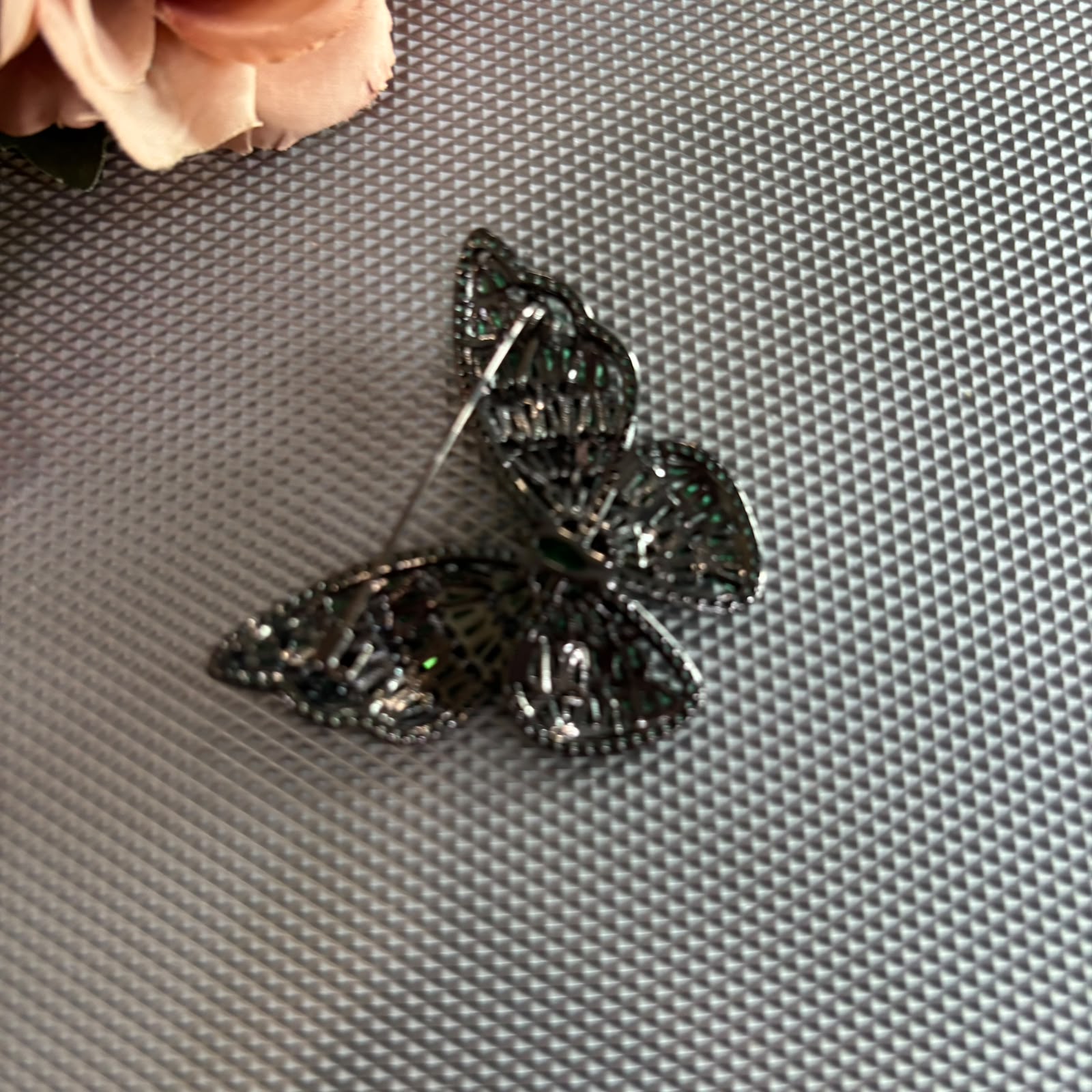 Emerald green crystal butterfly brooch with black rhodium finish and premium baguette stones.