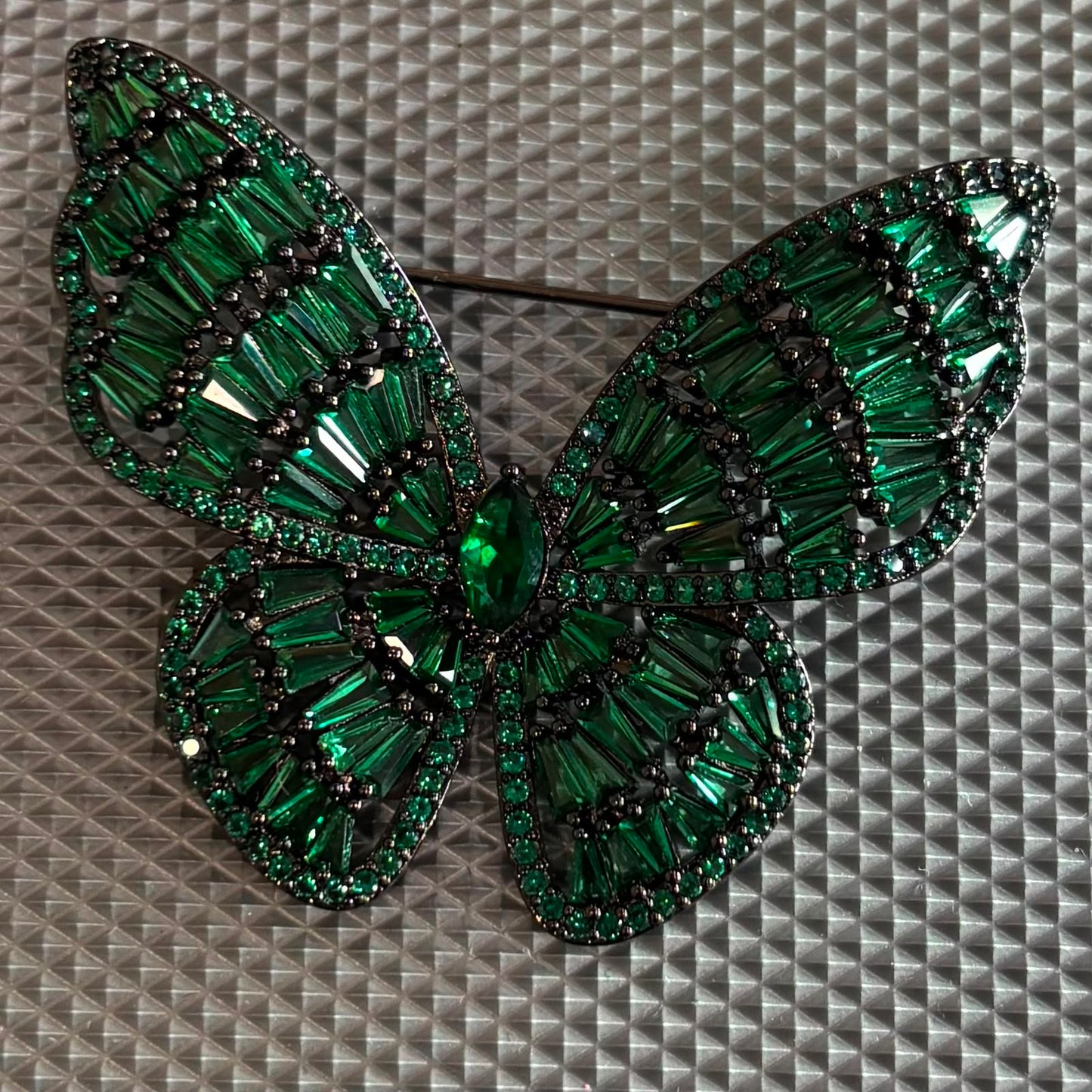 Emerald green crystal butterfly brooch with black rhodium finish and premium baguette stones.