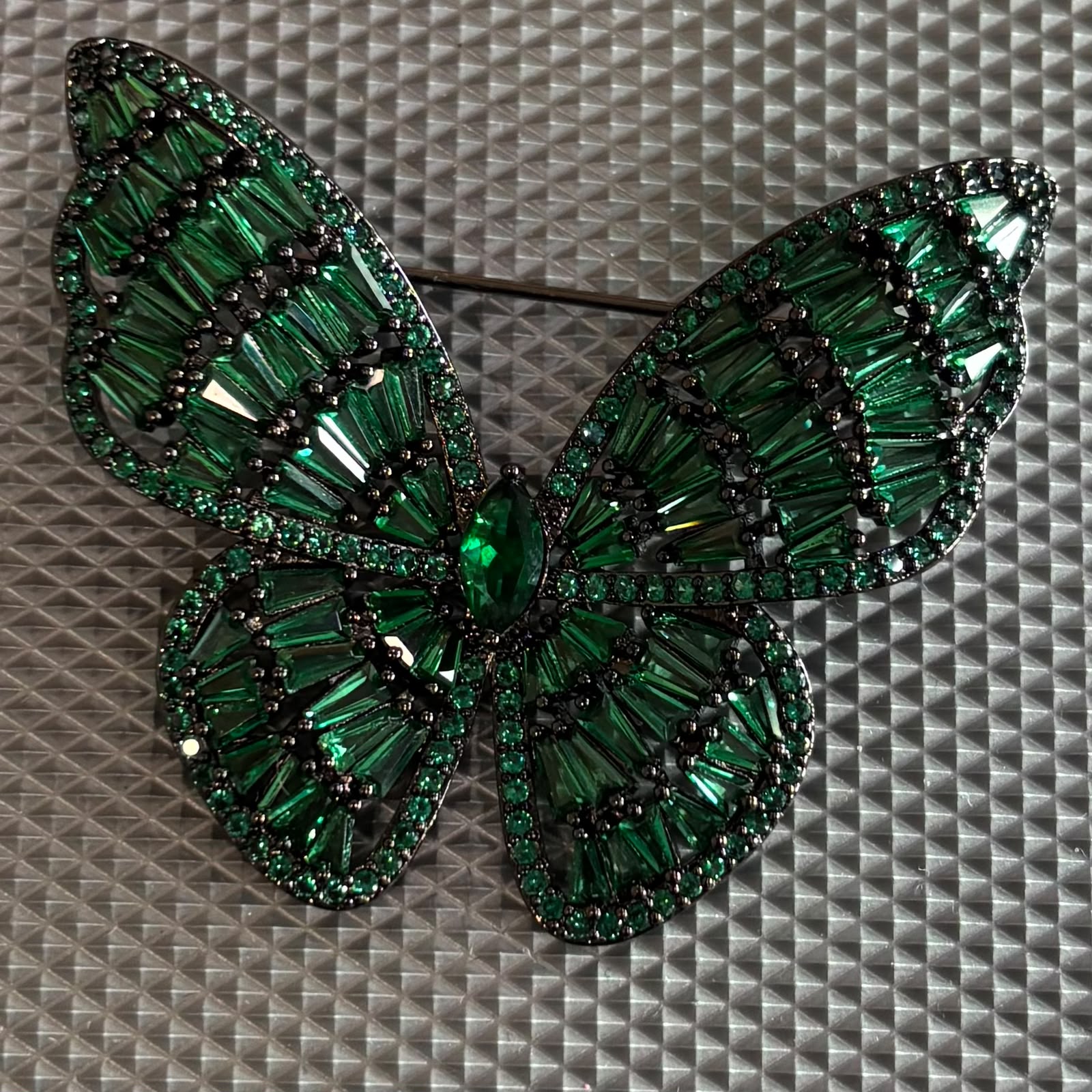 Emerald green crystal butterfly brooch with black rhodium finish and premium baguette stones.