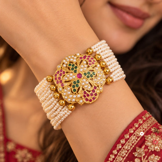 Close up of woman wearing Multistone Jadau bracelet with ivory pearl bead strands and floral centrepiece with hook and extension chain