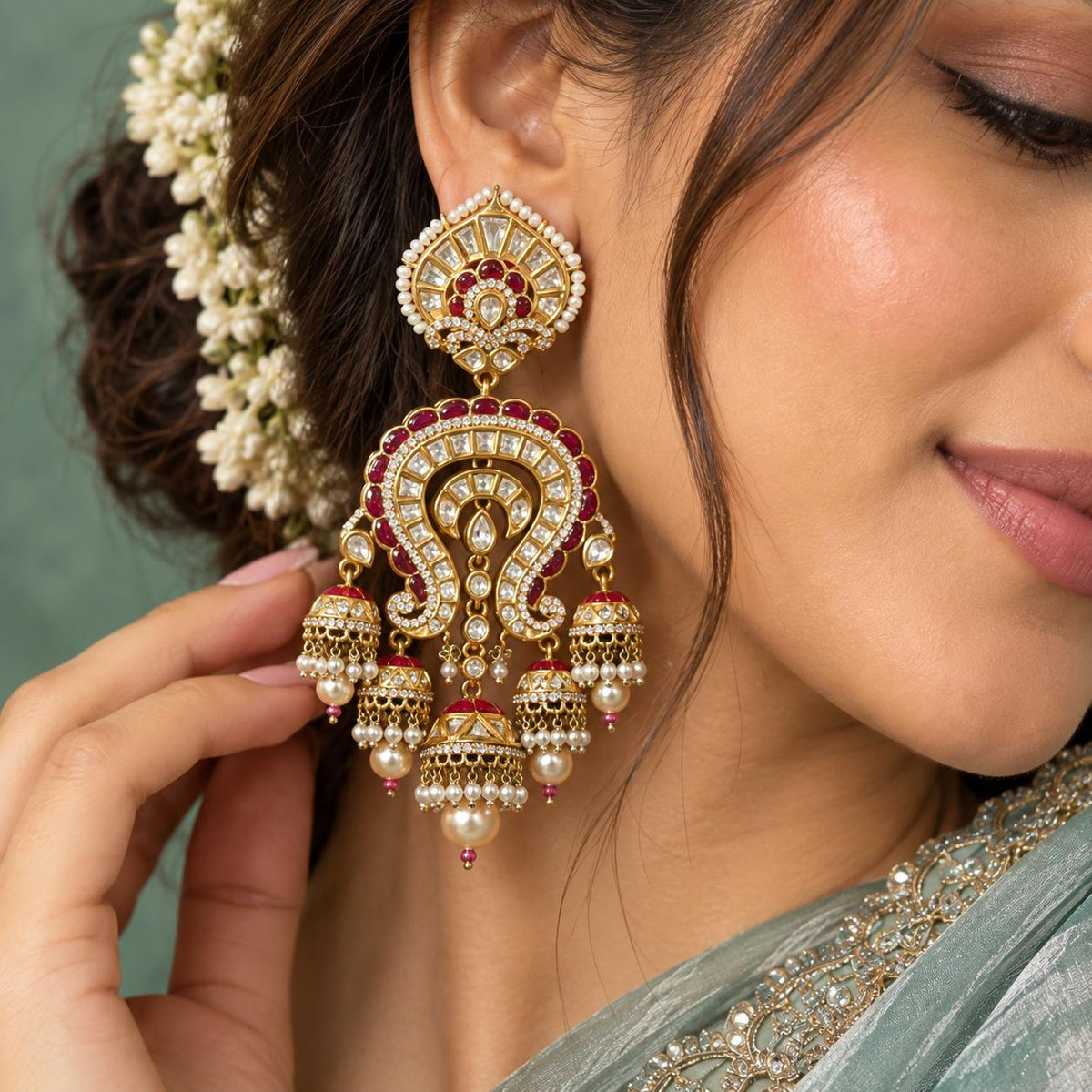 Close up of Woman wearing Rani ruby Kundan chandbali jhumka earrings with pearl drops and gold-tone finish