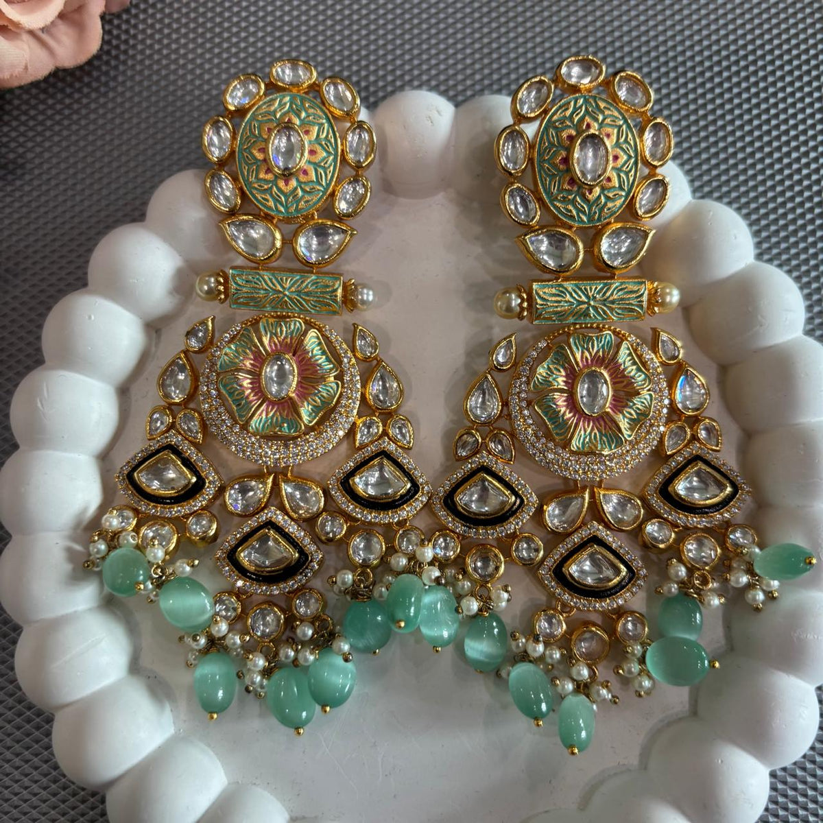 Close up of Mint green Meenakari-style statement earrings with clear stones and mint green beads  drops displayed on a white tray