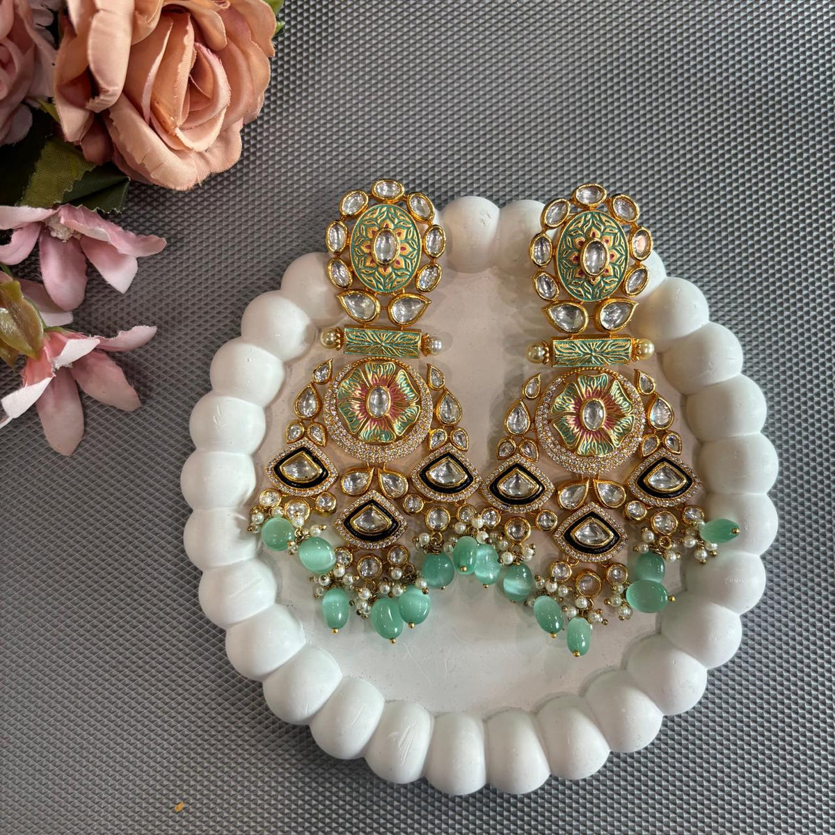 Mint green Meenakari-style statement earrings with clear stones and mint green beads  drops displayed on a white tray
