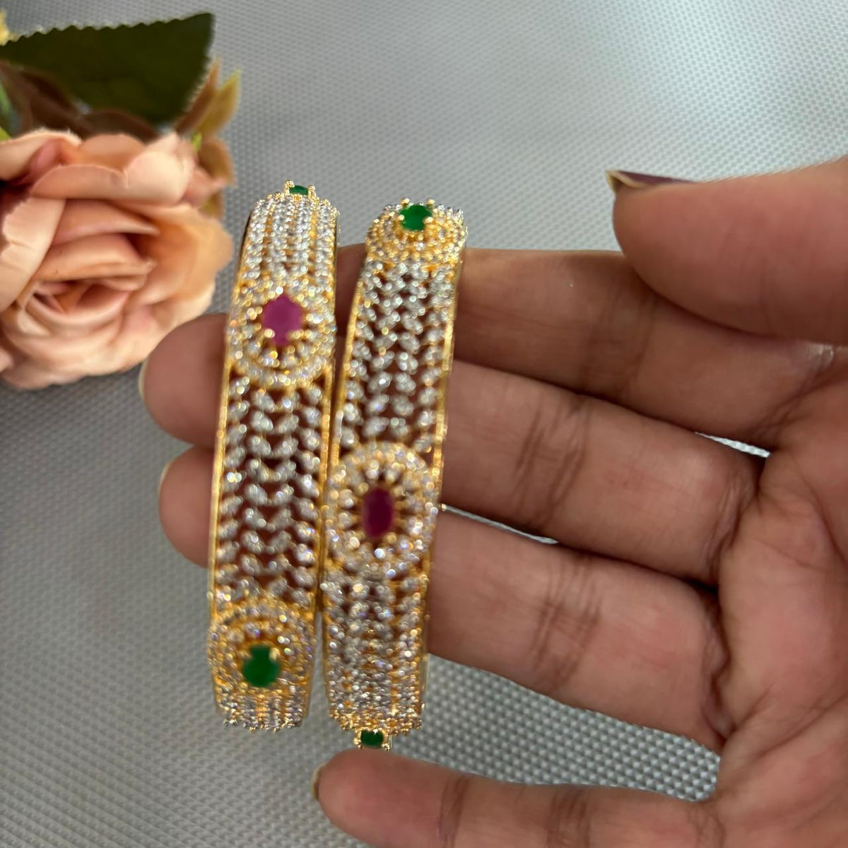 Close up of pair of  ruby emerald american diamonds gold tone Bangles 

