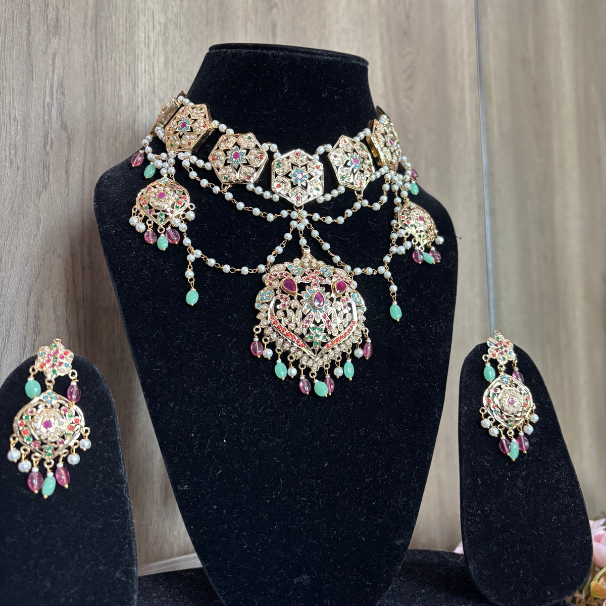 Anarkali multicolour Jadau necklace set with pearl strands and matching earrings on a black display bust