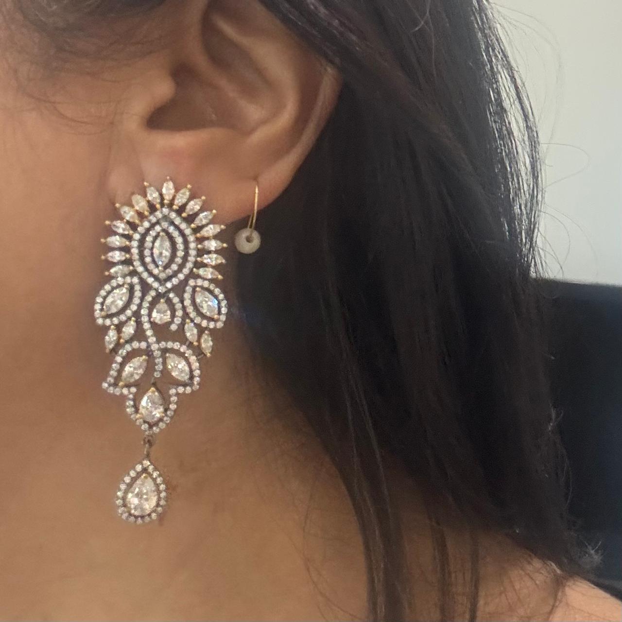 Woman wearing marquise American Diamond statement drop earrings with pear-shaped dangling stone in rhodium finish