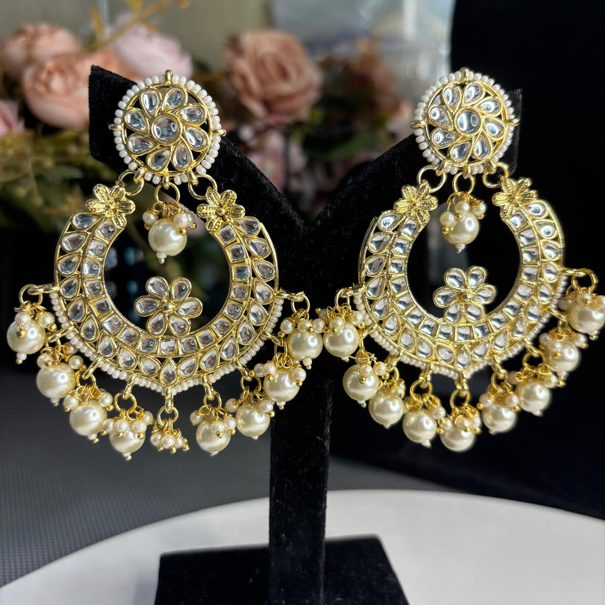 Oversized Indian chandbali earrings with Kundan-style stones and pearls on display