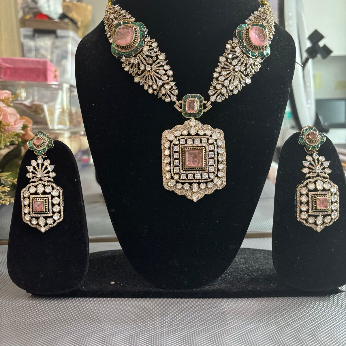 Front view of Kai Polki and AD necklace set displayed on black jewellery stands