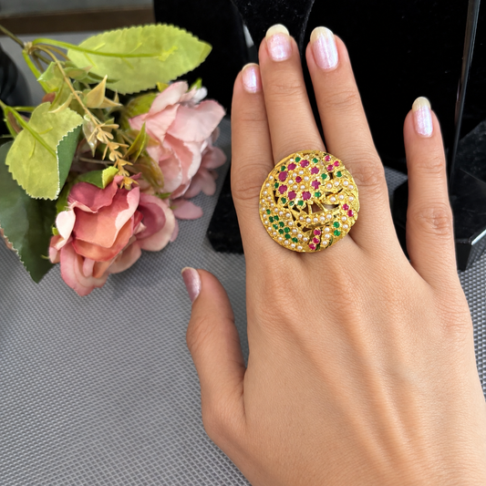 Maahi multicolour Jadau floral statement ring with pink and green stones and pearl details on a hand beside pink flowers